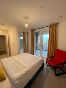 een slaapkamer met een bed, een rode stoel en een raam bij The Velvet Vista in Croydon