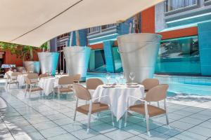 ヨハネスブルグにあるAfrican Pride Melrose Arch, Autograph Collectionのテーブルと椅子のあるレストラン、プールを提供しています。