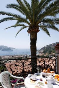 a table with food and a palm tree on a balcony at Hôtel La Flore in Villefranche-sur-Mer