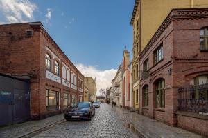 a car parked on a cobblestone street between buildings at Sunset Apartaments - Sunflower i Panorama in Toruń
