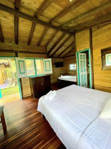 Cette chambre en bois comprend un lit blanc. dans l'établissement Hotel Karlaká Calarcá Quindio, à Calarcá