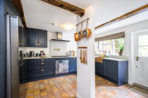 a kitchen with blue cabinets and a sink at Luxury 3 Bed Manor House HotTub Cinema in Saffron Walden
