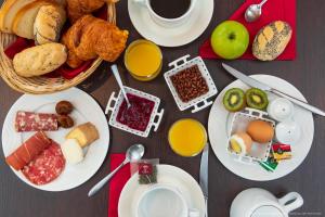 een tafel met borden ontbijtproducten en een kopje koffie bij La Maison Blanche in Sangatte