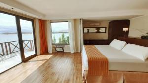um quarto de hotel com uma cama grande e janelas grandes em Xelena Hotel & Suites em El Calafate