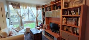 Chez Catherine في Fontenay-le-Fleury: غرفة معيشة مع تلفزيون ورف كتاب
