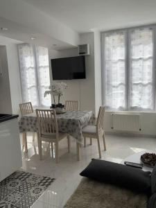 a dining room with a table and chairs and a television at Appartement 2 pièces RDC in Rambouillet