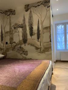 a bedroom with a mural of trees on the wall at Appartement 2 pièces RDC in Rambouillet