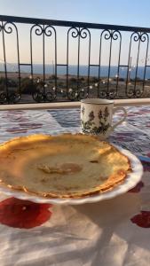 a pie sitting on a plate on a table with a cup at Dar Hachemia in Ras El Ma