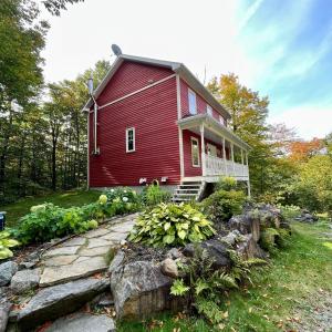 a red house with a stone path in front of it at Nature retreat with HOT TUB and lake access & watercraft in Saint Adolphe D'Howard +73 photos