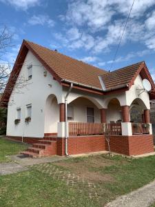 a white and red house with a brick wall at Pusztavár-Lak in Erdőhorváti