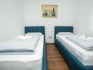 two beds in a room with a picture on the wall at Apartmani Mikic in Palić