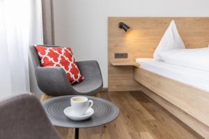 una habitación con una silla y una taza de café sobre una mesa en Gasthof Zum Roten Haus, 