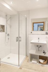 La salle de bains blanche est pourvue d'une douche et d'un lavabo. dans l'établissement Gasthof Zum Roten Haus, 
