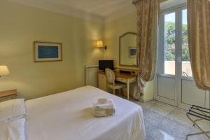 a bedroom with a bed and a desk and a window at Ena Hotel in Arenzano