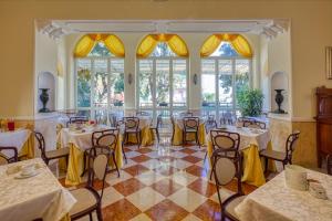 a banquet hall with tables and chairs and windows at Ena Hotel in Arenzano