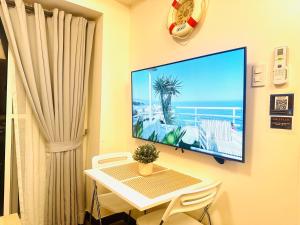 a room with a table and a tv on a wall at CELANDINE Residence by DMCI in Manila