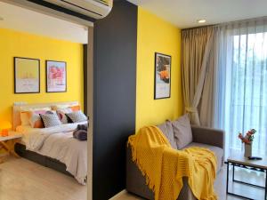 a bedroom with yellow walls and a bed and a chair at Palm Springs Fountain Nimman Condominium in Chiang Mai