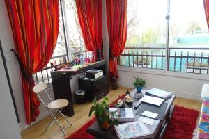 um quarto com cortinas vermelhas e uma secretária em frente a uma janela em La bambouseraie em Montrouge