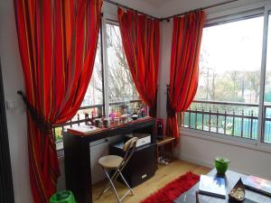 Habitación con cortinas rojas y escritorio frente a una ventana. en La bambouseraie, en Montrouge