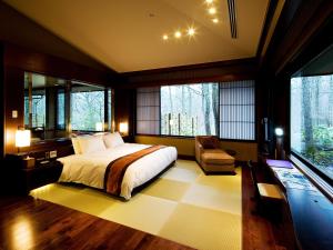 1 dormitorio con 1 cama, 1 silla y ventanas en 竹泉荘 Chikusenso Onsen en Zao