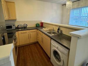 a kitchen with a sink and a washing machine at Manchester flat close to City Centre and Stadium in Manchester