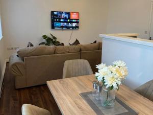 a living room with a couch and a table with flowers at Manchester flat close to City Centre and Stadium in Manchester