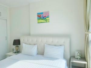 1 dormitorio con cama blanca y almohadas blancas en Căn hộ Vinhomes Central Park- CityLights Premium Apartment, en Ho Chi Minh