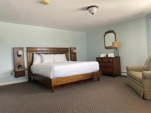 una camera con letto, sedia e specchio di The Wildflower Inn a Lyndonville