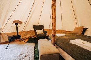 a room with a bed and a chair in a tent at Luxury Boutique Camping in Selfoss