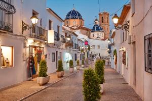 an alley with potted trees and buildings with a church at Altea Serenity in Altea