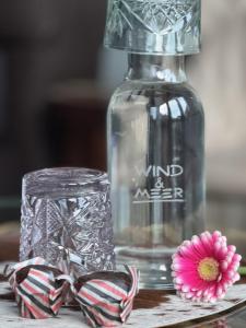a glass bottle with a pink flower next to a candle at Gästehaus Wind und Meer in Norddeich