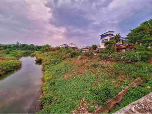 uma casa no topo de uma colina ao lado de um rio em โรงแรมริเวอร์เลย แกรนด์วิว em Wang Saphung