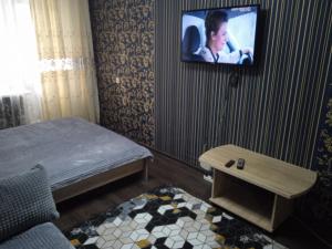 Zimmer mit einem Bett und einem TV an der Wand in der Unterkunft Апартаменты посуточно по Ауэзова in Öskemen