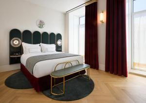 sypialnia z dużym łóżkiem i krzesłem w obiekcie Montebelo Vista Alegre Lisboa Chiado Hotel w Lizbonie