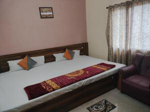 a bedroom with a bed and a chair at Milan Palace Deoghar in Deoghar