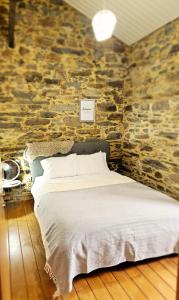 a bed in a room with a stone wall at PampiHouse in Pampilhosa da Serra