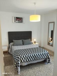 a bedroom with a bed with a checkered blanket on it at Apartamento Vicsus in Ajo
