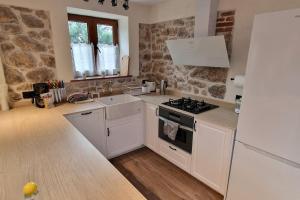 eine Küche mit weißen Geräten und einer Steinmauer in der Unterkunft La Casina de Mestas de Con - Con jardín exterior - VV-2903-AS in Con