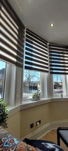 a living room with three windows with blinds at Paisley Pattern Flat West End UWS UNI GLA Glasgow Airport in Elderslie