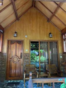 Casa de madera con sillas y puerta de madera en Sunny Rose Bungalows Gili Air en Gili Air