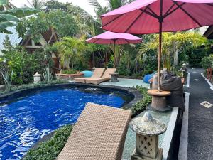 uma piscina com um guarda-sol e cadeiras e uma mesa com em Sunny Rose Bungalows Gili Air em Gili Air