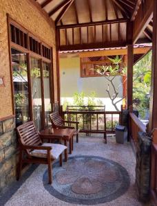 un patio con 2 sillas, una mesa y una mesa en Sunny Rose Bungalows Gili Air, en Gili Air