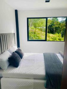 een slaapkamer met een wit bed en een raam bij Casa Blanca Cabaña de lujo rodeada de naturaleza in Copacabana