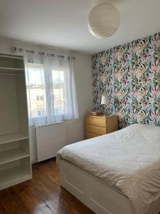 Schlafzimmer mit einem Bett mit Blumentapete in der Unterkunft La maison du BONHEUR in Sucy-en-Brie