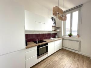 a kitchen with white cabinets and a sink at Chez Alexia et Vincent in Lille