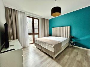 a bedroom with a bed and a blue wall at Sopot Marina Beach Suites in Sopot