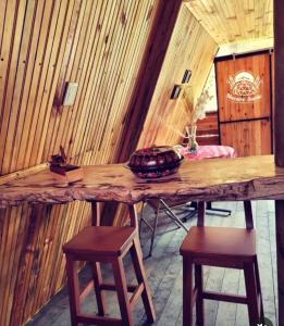 una mesa de madera con taburetes en una habitación con paredes de madera en Glamping y Cabañas Alpina, en Buga