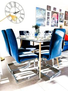 a dining room table with blue chairs and a clock at 3Bed House For Contractors Large Group Sleep upto9 in Birmingham