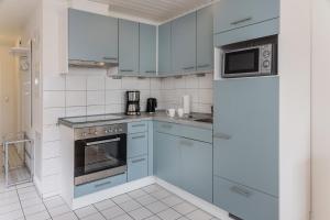eine Küche mit blauen Schränken und einem Kühlschrank in der Unterkunft 50187... in Harlesiel + 8 Fotos