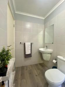 a white bathroom with a toilet and a sink at Stay on Main - Studio Blue in Paarl